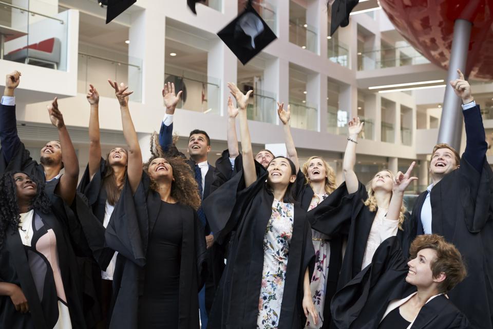 Ferdigutdannede universitetsstudenter kaster hattene sine opp i lufta.